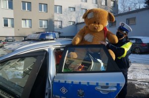 policjantka trzyma pluszaka stoi obok radiowozu