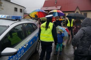 policjantka stoi tyłem obok radiowozu w tle osoby