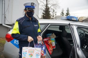 policjantka stoi przed radiowozem i trzyma paczki