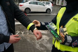 fragment policjanta i osoby z założonym na ręce odblaskiem