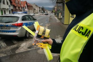 policjnatka trzyma odblaski w tel readiowóz i ulica