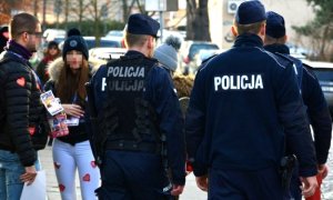 policjanci stoją tyłem w tle osoby