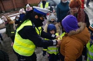 policjantka zakłada odblaski obok dzieci