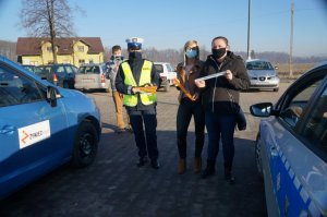 policjantka stoi obok dwie kobiety z odblaskami obok samochody