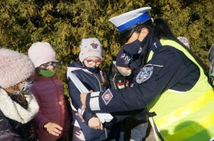 policjantka wręcza odblaski dzieciom