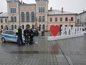 policjant obok radiowozu obok stoją trzy kobiety z odblaskami w tle rynek w Żywcu