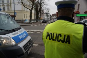 policjant stoi tyłem w tle ulica i skrzyżowanie