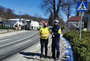 stoi  policjant obok kobieta i trzyma w rękach odblaski