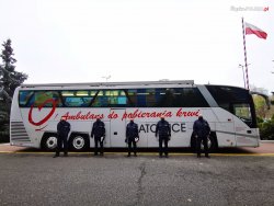 ambulans krwiodastwa przed nim stoją policjanci zdjęcie kolorowe