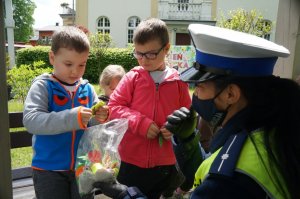 policjantka wręcza dzieciom odblaskowe zawieszki