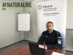 policjant siedzi przy biurku przed komputerem w tle baner