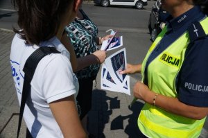 fragment policjantki wręczającej ulotki i odblaski