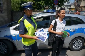 policjantka i pracownik z WORD w bielsku białej stoją na tle radiowozu i trzymają ulotki