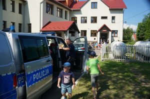 dzieci w radiowozie obok policjant