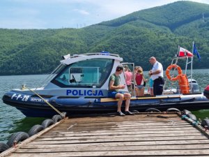 zdjęcie pomostu na końcu kórego jest policjna motorówka w środku niej dzieci oraz policjant