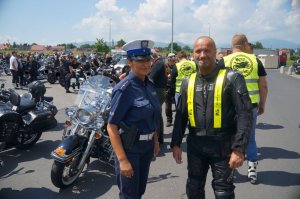 stoi motocyklista obok niego policjantka w tle motory i inny motocykliści