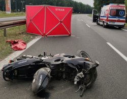 na pierwszym planie leżący na ziemi motocykl w tle parawan i karteka