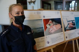 z lewej strony zdjęcia stoi policjantka obok niej sztalugi z plakatami