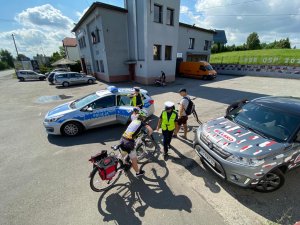 stojące radiowozy i wóz radia bielsko policjanci i rowerzysta na placu