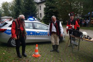 mężczyźni w przebraniu zbójeckim w założonych alkogooglach pokonują slalom w tle radiowóz