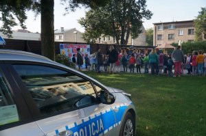 fragment radiowozu dzieci na zewnątzr i policjantka