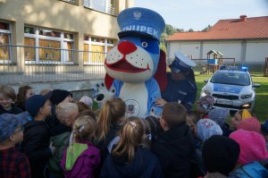 policjantka i sznupek przed nimi stoją dzieci w tle radiowóz