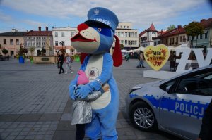 dziewczynka przytula się do sznupka obok radiowóż w tle rynek i miasto