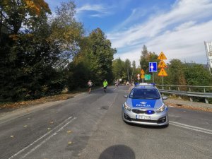 radiowóz w tle po drodze biegną biegacze