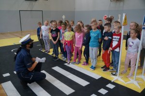 policjantka tłumaczy dzieciom zasady bezpieczeństwa w ruchu drogowym dzieci stoją na przeciw niej