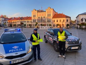 na żywieckim rynku zaparkowany radiowóz i samochód radia bielsko obok stoi policjantka i redaktor który trzyma odblaski