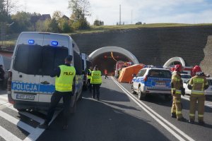 zaparkowane przed tunelem wozu służb ratunkowych i policji obok policjanci i strażacy