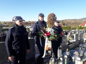 policjanci stoją przed grobem z wiązankami