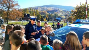 policjantka stoi przy radiowozie obok stoją dzieci