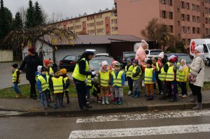 dzieci stoją z policjantką przed przejściem dla pieszych