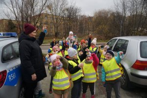 dzieci stojąobok radiowozu i trzymają odblaskowe zawieszki