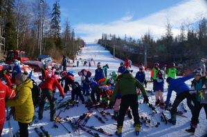 na pierwszym planie grupa narciarxzy w trakcie rozgrzewki w tle stok