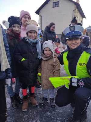 policjantka obok dzieci trzymających odblaski
