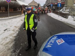 policjantka i radiowóz na pierwszym planie w tel ulica z kolędownikami