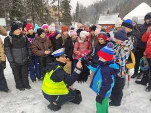 policjantka wręcza dziecku odblask obok stoją inne dzieci