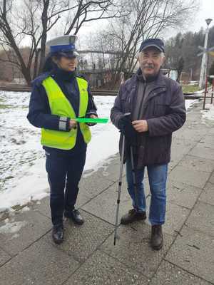 policjantka która trzyma odblaski obok stoi pieszy