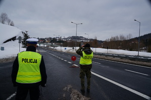 policjant stoi tyłem obok funkcjonariusz straży granicznej w tle ulica