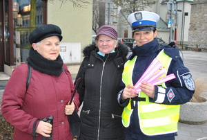 policjantka obok której stoją dwie kobiety trzymające odblaski