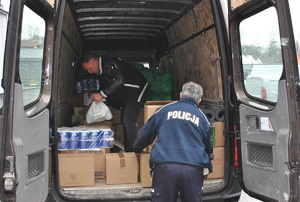 policjant wkłada kartony do samochodu