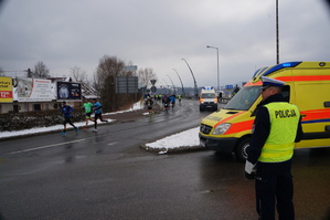 na drodze stoi policjant obok stoi karetka pogotowia na drodze biegną bieczace