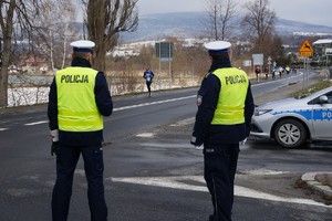 policjanci stoją obok radiowozu w tle ulica oraz biegacze