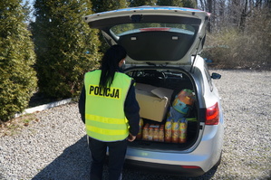 policjantka stoi tyłem przy radiowozie w bagażniku widać artykuły przeznaczone dla dzieci