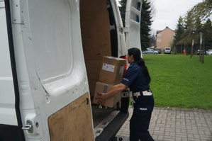 policjantka wkłada do samochodu kartonowe pudełka