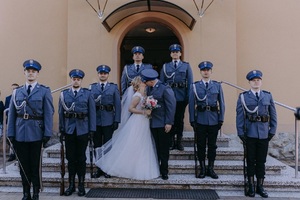 na schodach stoi młoda para obok policjanci z kompanii honorowej