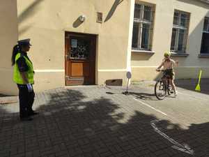 policjantka stoi po lewej stronie obok po torze jedzie rowerzystka