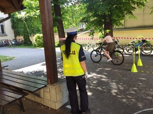 policjantka stoi tyłem po torze jedzie uczeń na rowerze